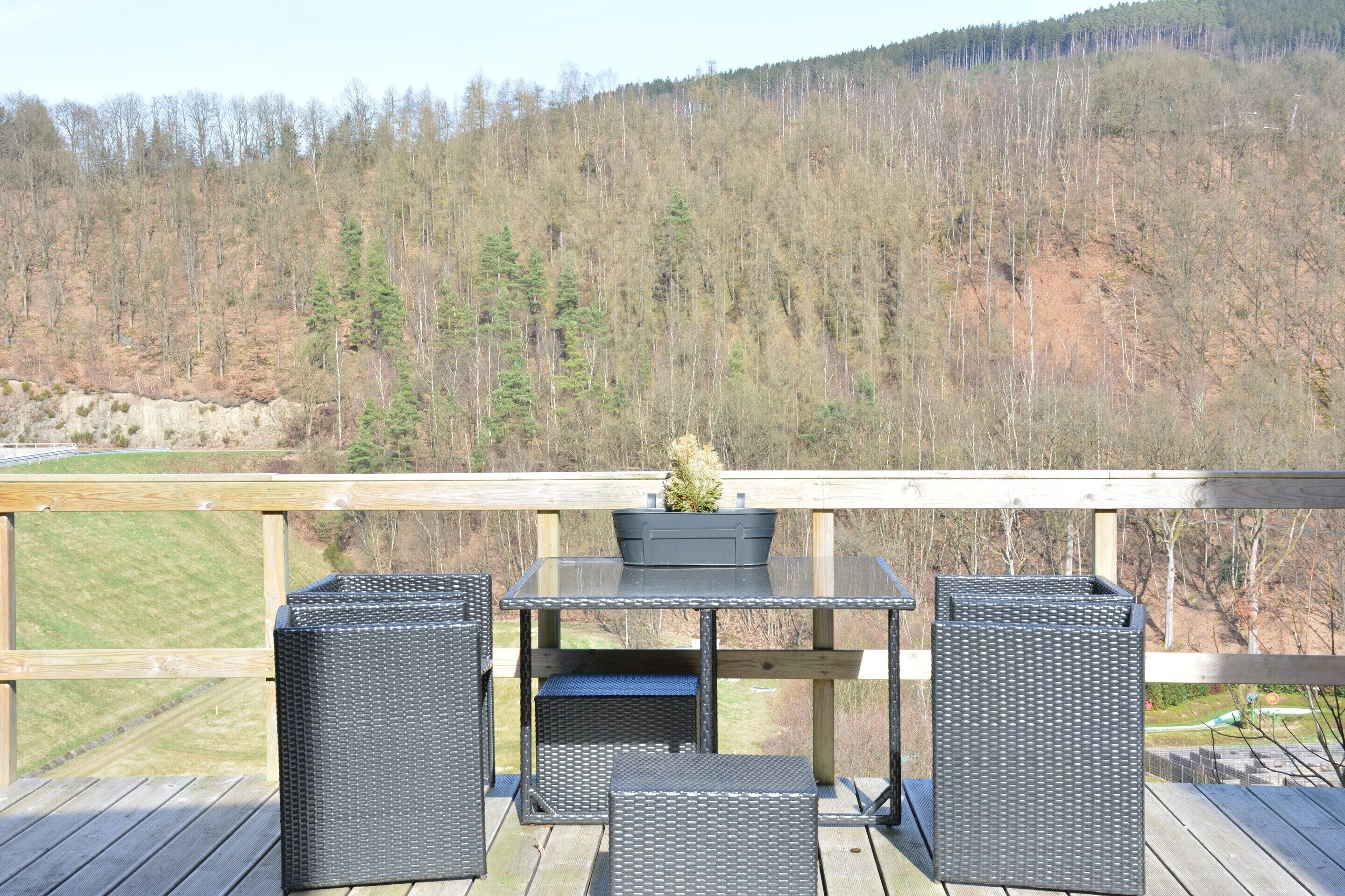 Eine Terrasse mit einem Tisch aus Glasplatten, zwei Korbstühlen und einem Blumentopf.
