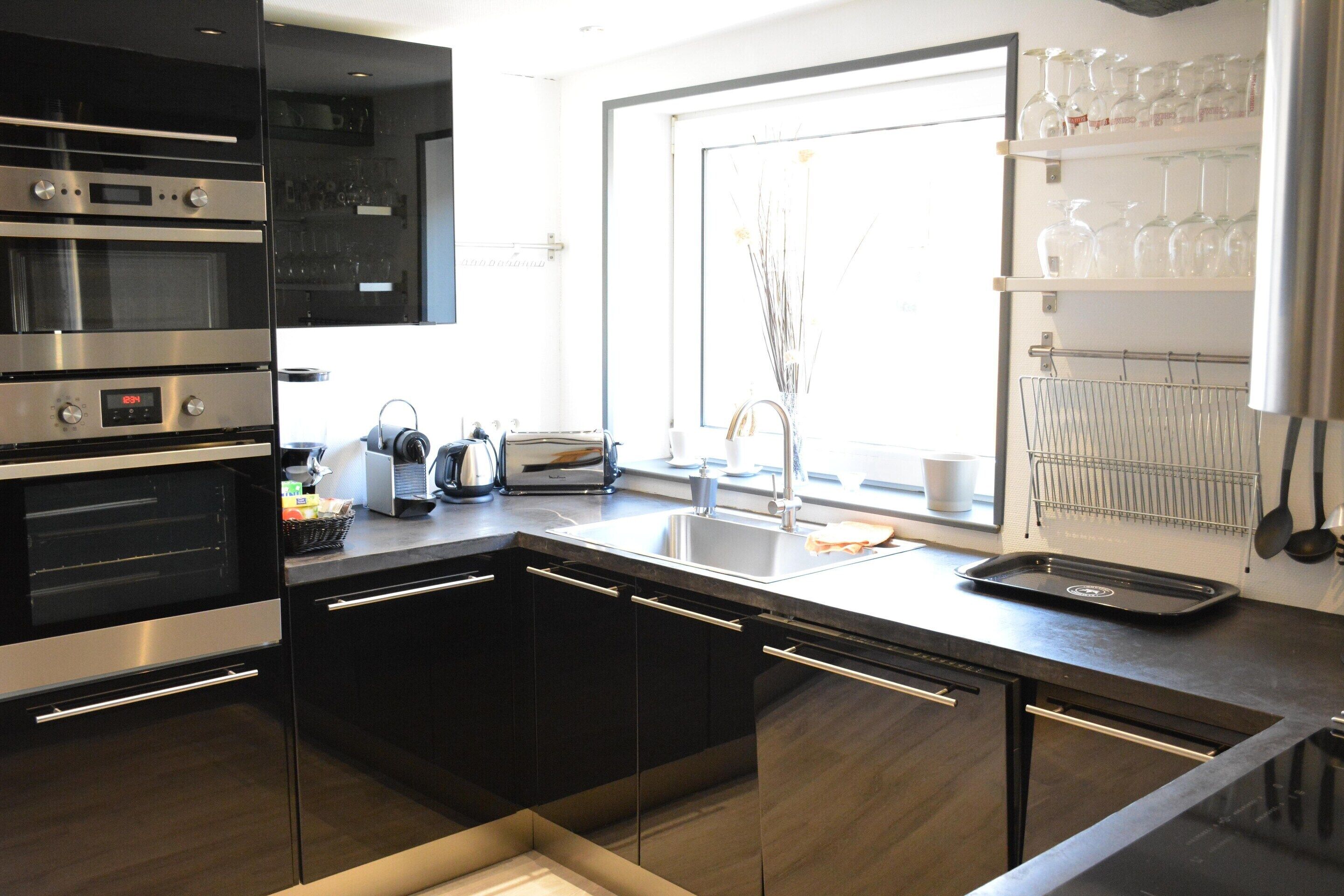 A modern kitchen with built-in ovens, a sink, and a window with a view.