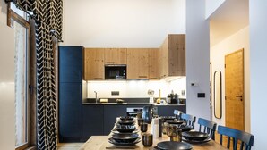A modern kitchen with wooden cabinets, a black countertop, and a dining area with a wooden table and chairs. - Apartment in La Chapelle Near Ski Lift (La Chapelle-d'Abondance)
