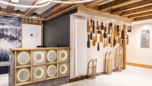 A reception area with a wooden reception desk, a wall with various wooden utensils, and a sign indicating the location of the chalet. - Apartment in La Chapelle Near Ski Lift (La Chapelle-d'Abondance)