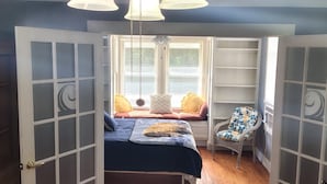 Een slaapkamer met een bed, een stoel en een raam met zonwering.