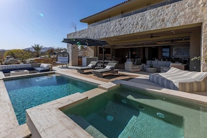 Uma casa moderna com piscina, área de estar externa e fachada de pedra.