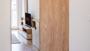 Ein modernes Wohnzimmer mit einer Holzvertäfelung, einem Flachbildfernseher und einem Blumentopf.