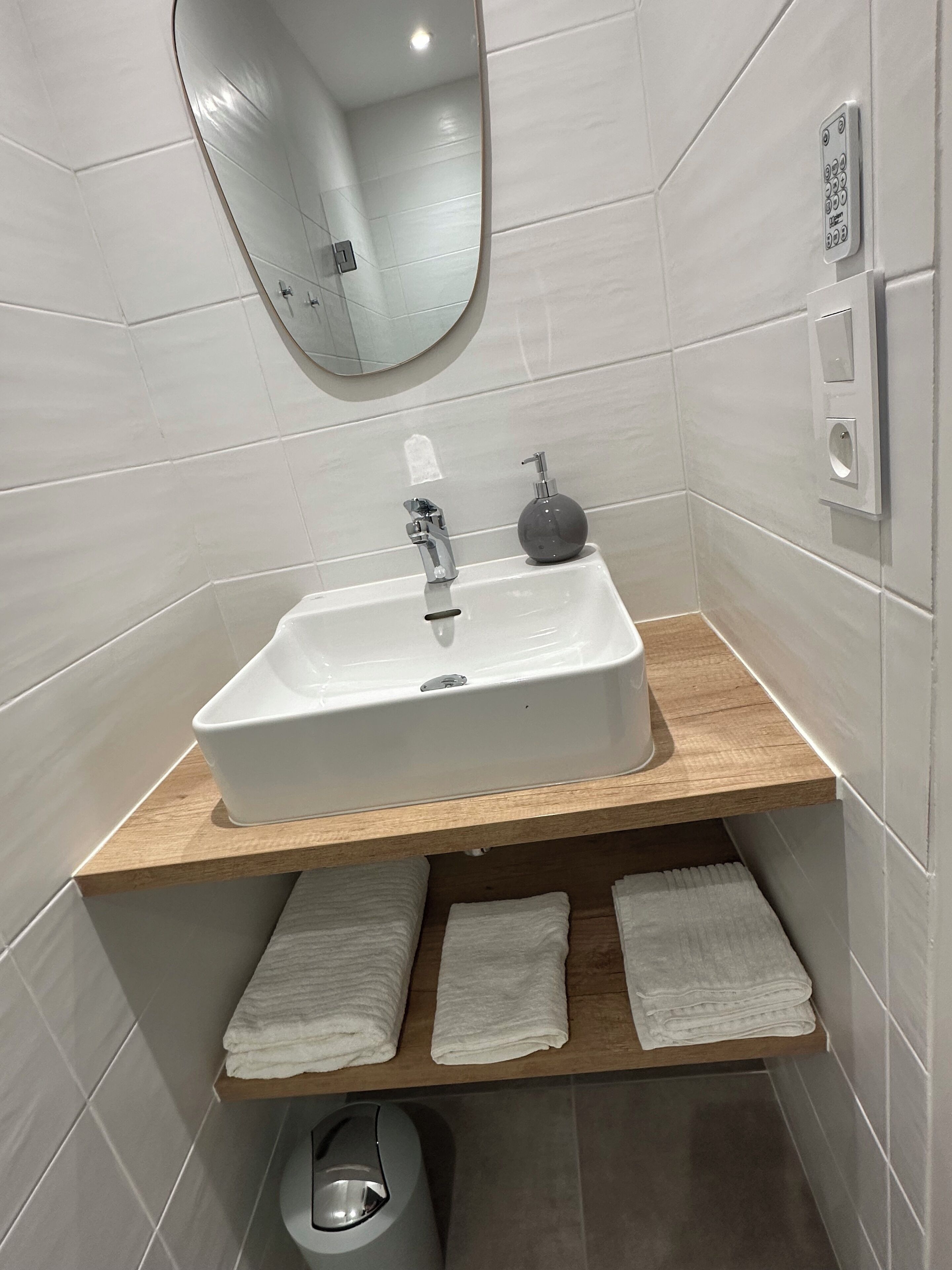 Een badkamer met een wit wastafel, een houten plank en een spiegel.