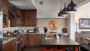 A modern kitchen with wooden cabinets, stainless steel appliances, a central island, and pendant lighting. - 10 Trails Edge-Curate Telluride, Ski-in/out, Walk to Gondola, Market, Hot Tub (Mountain Village)