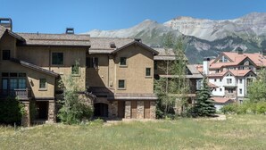 A residential area with houses featuring stone and stucco exteriors, set against a backdrop of mountains.