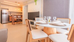 Una cucina moderna con frigorifero integrato, mobili in legno e zona pranzo con tavolo rotondo per quattro persone.