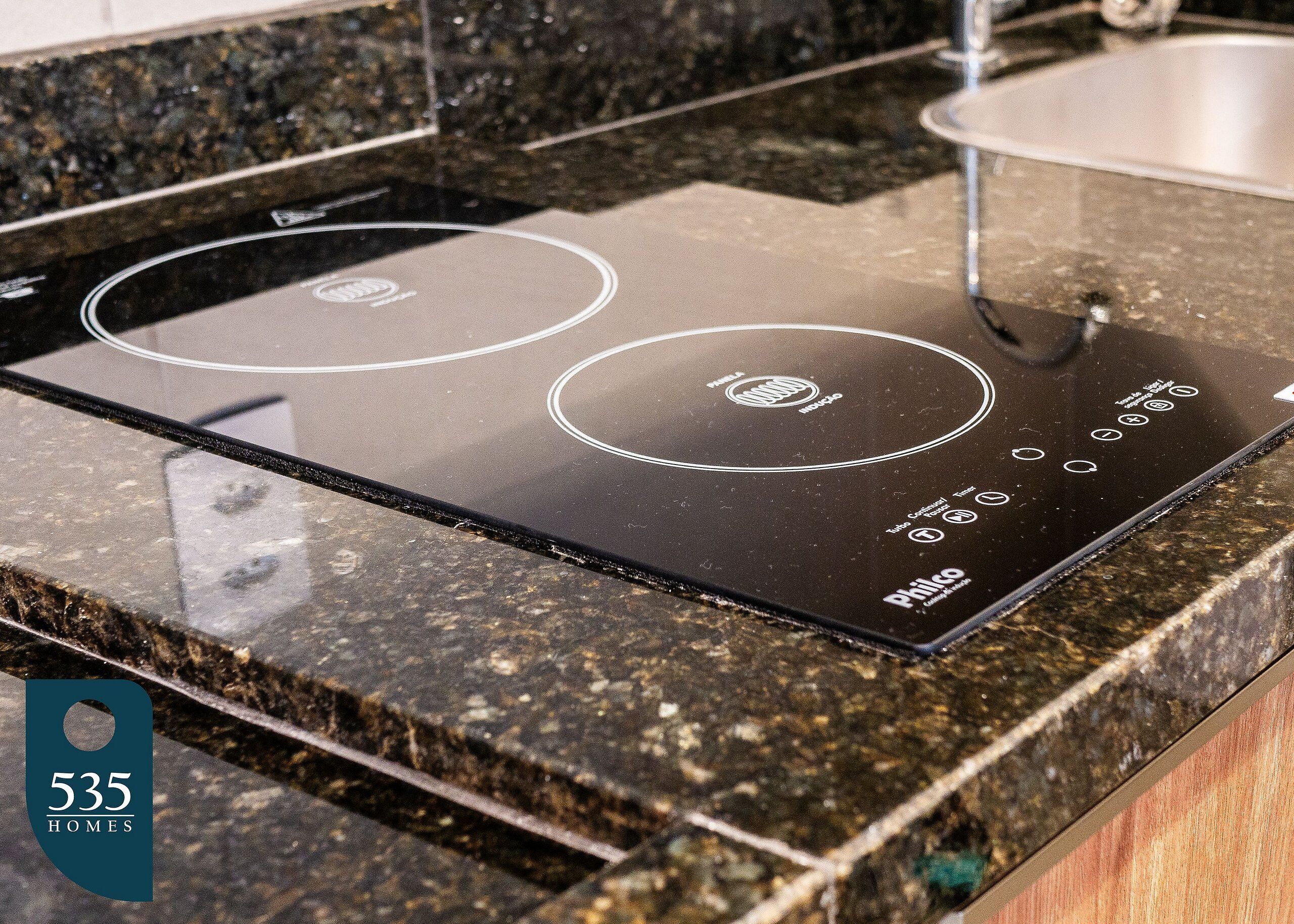 Une cuisine dotée d’une plaque de cuisson à induction noire et d’un évier en acier inoxydable.