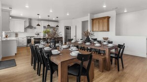 A modern kitchen with white cabinets, a wooden dining table set for six, and black chairs. - [The Grandview] Pool, Pickleball, Hot Tub, Views (Page)