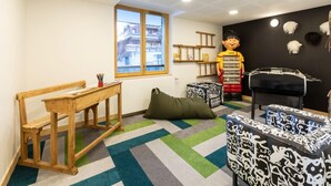 A children's playroom with a large window, a wooden bench, a green bean bag, and a black and white patterned ottoman. - Apartment in Les Deux Alpes Near Ski Slopes (Les Deux Alpes)