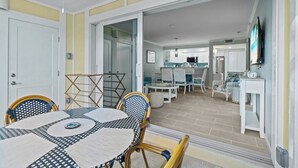 A dining area with a round table and chairs, a kitchen in the background, and a TV mounted on the wall.