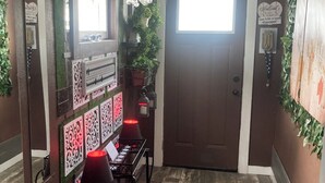 A hallway with a brown door, decorative wall panels, a chandelier, and a welcome sign.