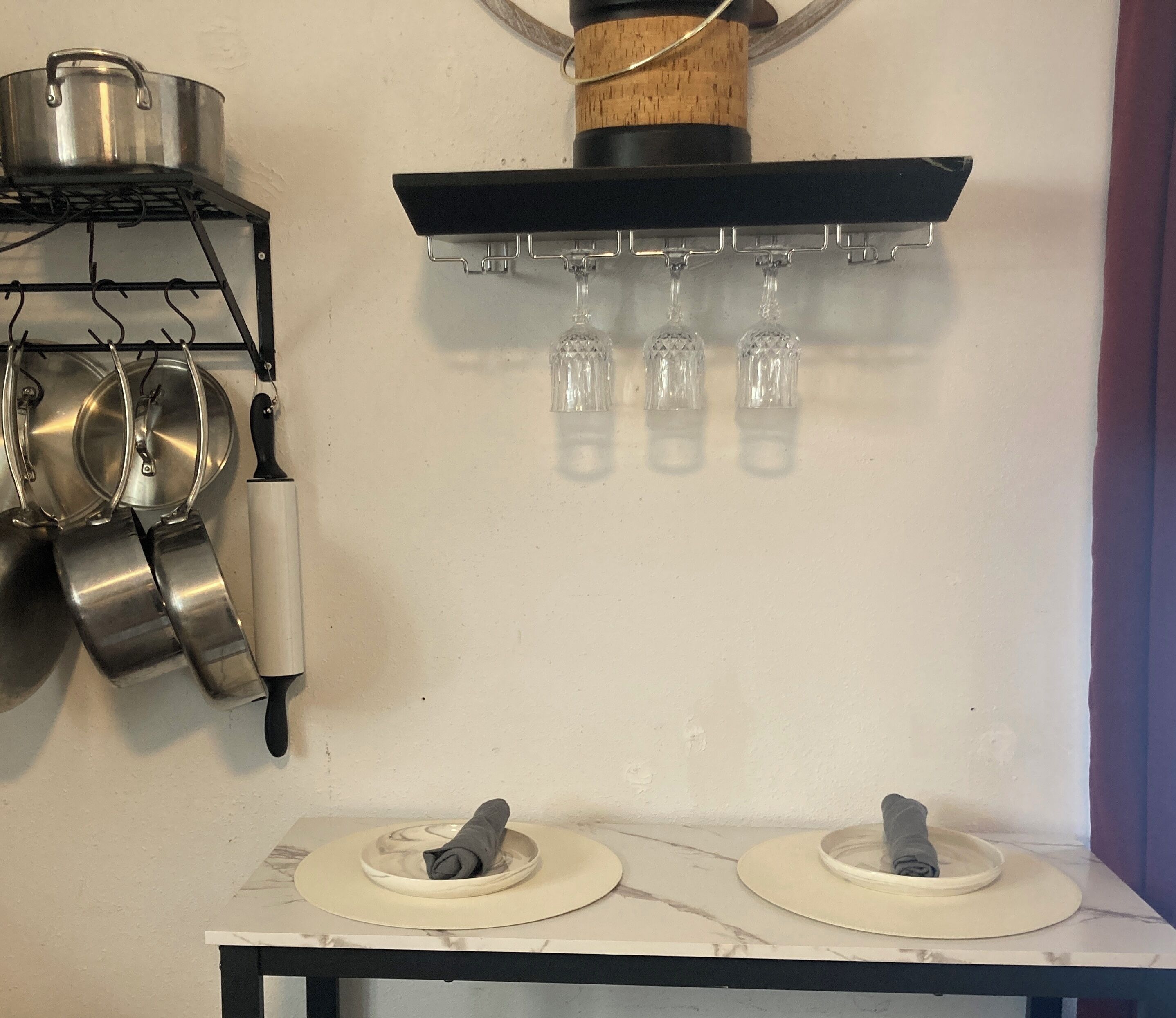 Eine Küche mit Gasherd, hängenden Töpfen, einem Weinregal und zwei Schüsseln mit Handtüchern.