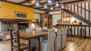 A dining area with a wooden table and chairs, a fireplace, and a staircase leading to a kitchen area. - Villa Meer - Private villa, 5 bedrooms, pool, A/C, wifi, hot tub, Marche (Fano)