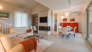 A modern living room with a fireplace, white furniture, and a dining area. - Villa Meer - Private villa, 5 bedrooms, pool, A/C, wifi, hot tub, Marche (Fano)