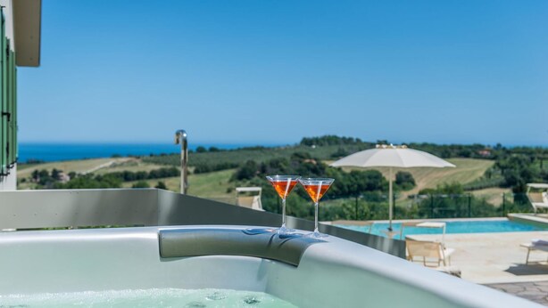 A hot tub with two martini glasses on a balcony overlooking a pool and a scenic view of the sea and hills. - Villa Meer - Private villa, 5 bedrooms, pool, A/C, wifi, hot tub, Marche (Fano)