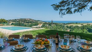 A dining table set for a meal with a view of a swimming pool and the sea. - Villa Meer - Private villa, 5 bedrooms, pool, A/C, wifi, hot tub, Marche (Fano)