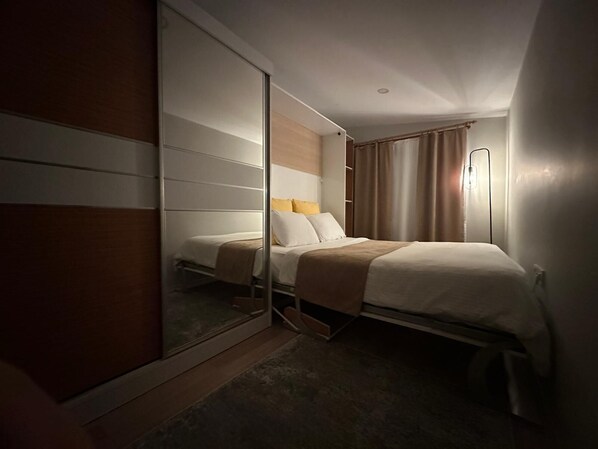 A hotel room with a bed, a wardrobe, and a mirror.