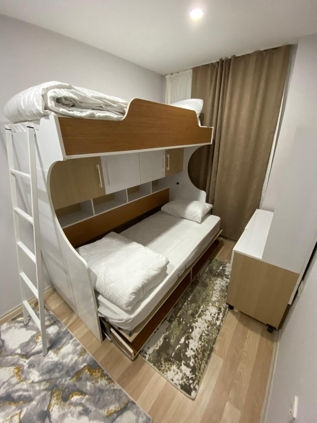 A compact room with a bunk bed, a desk, and a small seating area.