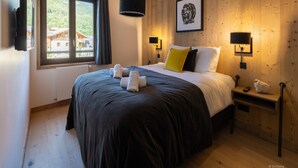 A bedroom with a large bed, two bedside lamps, a framed picture on the wall, and a window with curtains. - Apartment in Chantemerle Near Serre-chevalier (Saint-Chaffrey)