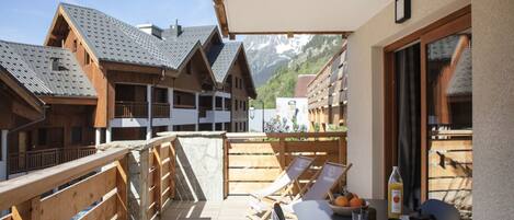 Ein Balkon mit Holzgeländern, einem Tisch und Stühlen sowie Bergblick.