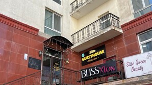 Un edificio con un'insegna per 'Elite Guesthouse' e il salone di bellezza 'BlissXlon'.