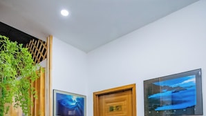 Un corridoio con una porta in legno con la scritta 'Greenpeace', un quadro appeso al muro e una pianta in vaso.