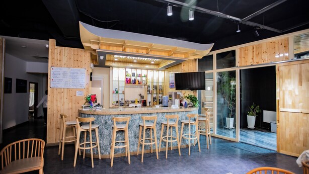 Angolo bar con sgabelli di legno, una lavagna con il menu e un bancone.