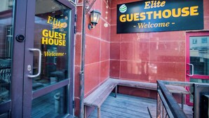 Un muro esterno con tegole rosse e un cartello che riporta 'Elite Guesthouse Welcome'.
