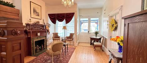 A spacious living room with a fireplace, wooden furniture, and a chandelier.
