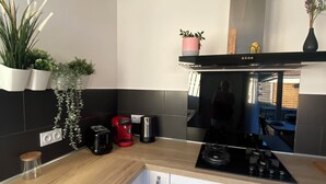 Una cucina moderna con mobili bianchi, un piano di lavoro in legno, un fornello nero e diverse piante in vaso.