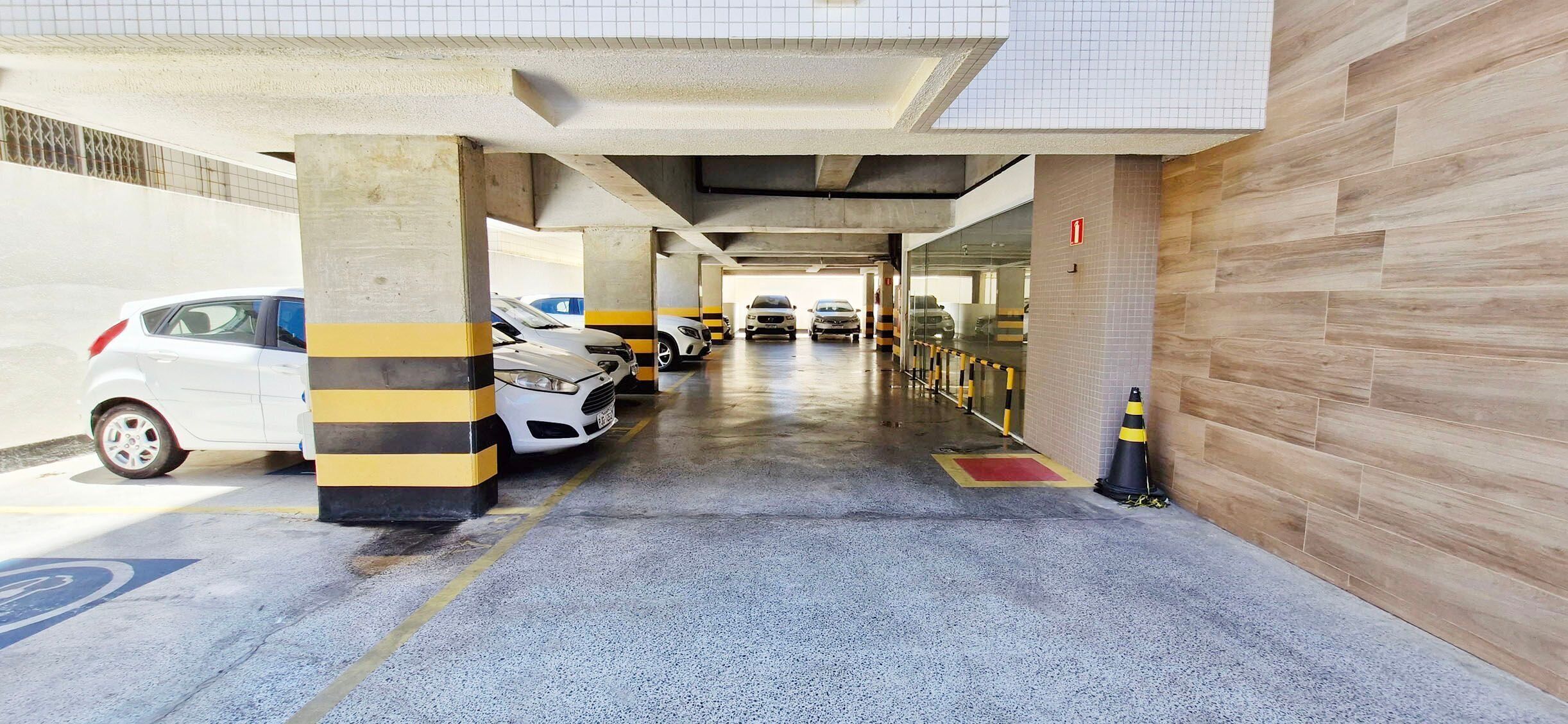 Un estacionamiento con varios coches aparcados bajo una cubierta.