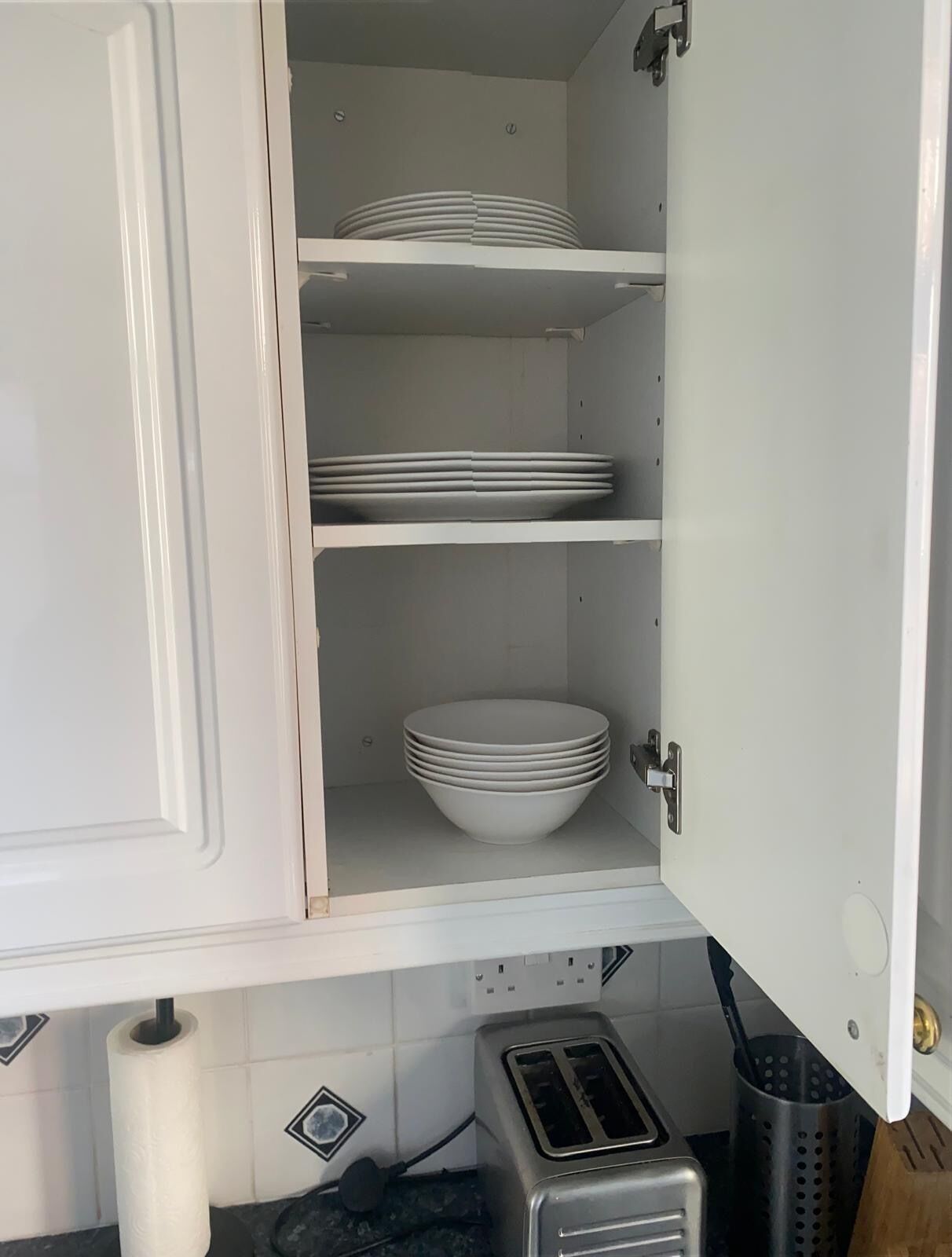Un meuble de cuisine avec un intérieur blanc et un grille-pain posé sur le plan de travail.
