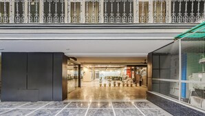 A spacious lobby with a marble floor, a metal railing, and a glass door leading to a restaurant. - Classic Cloud Bay (Gurugram)