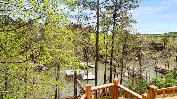 A wooden deck overlooking a forested area with a river and boats. - Thistle Brae - Dock Toys galore! And Pet-Friendly! (Houston)