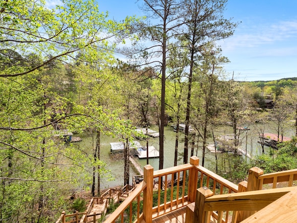 Une terrasse en bois donnant sur une zone boisée, avec une rivière et des bateaux.