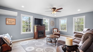 A living room with a fireplace, a television, and a ceiling fan. - Thistle Brae - Dock Toys galore! And Pet-Friendly! (Houston)