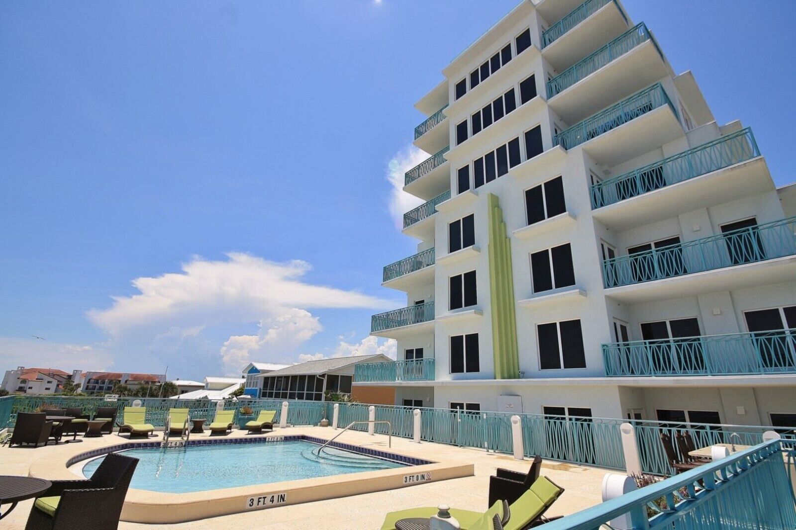 Un hôtel doté d’une piscine, d’un espace extérieur aménagé avec des sièges et d’un bâtiment à plusieurs étages avec des balcons.
