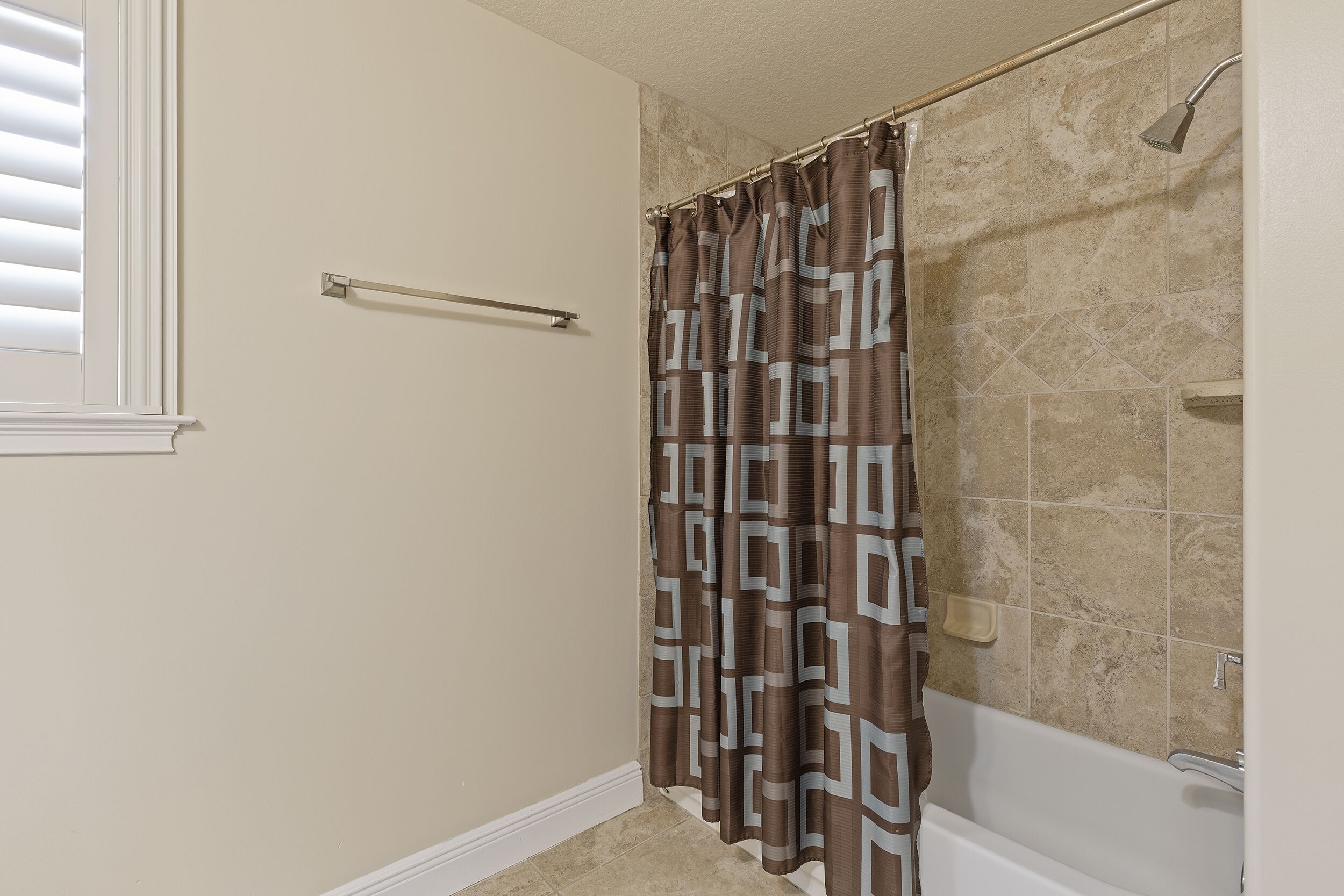 Une salle de bain avec un rideau de douche, un porte-serviettes et une baignoire.
