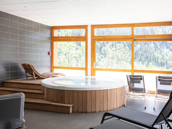 A spa area with a hot tub, wooden steps, and seating. - Apartment in Vaujany Near Alpe D'huez Slopes (Vaujany)