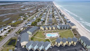 An aerial view of a coastal residential area with a beachfront, a swimming pool, and a parking lot. - Charming 2-bedroom condo with fitness room, WiFi in awesome Surf City (Surf City)