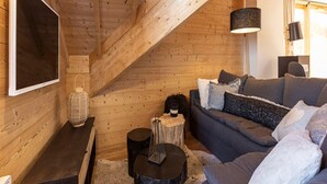 A cozy wooden interior with a sofa, a TV, and a lamp. - Apartment in Vaujany Near Alpe D'huez (Vaujany)