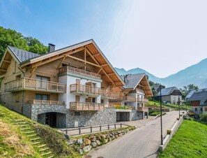 Un chalet à plusieurs étages, avec des murs en pierre, des balcons en bois et une vue imprenable sur les montagnes.