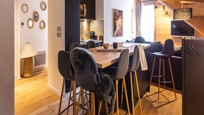 A modern kitchen with a wooden ceiling, a dining area with bar stools, and a kitchen island. - Apartment in Vaujany Near Alpe D'huez (Vaujany)