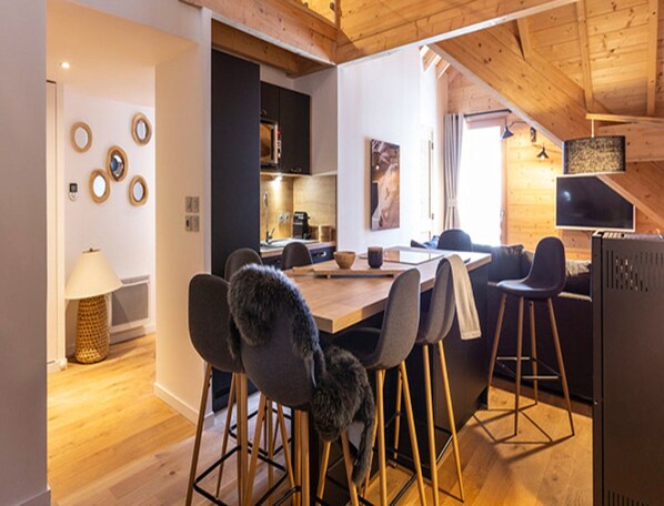 Une cuisine moderne avec un plafond en bois, un coin repas doté de tabourets de bar et un îlot central.
