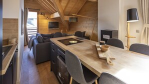 A modern kitchen with a wooden table, grey chairs, and a built-in oven. - Apartment in Vaujany Near Alpe D'huez (Vaujany)