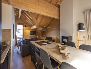 A modern kitchen with a wooden table, grey chairs, and a built-in oven.