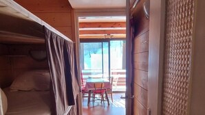 Un corridoio stretto con un letto a castello a sinistra e una porta con pannello decorativo a destra.