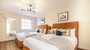 Une chambre d’hôtel avec deux lits, une grande fenêtre, un miroir et un lustre.