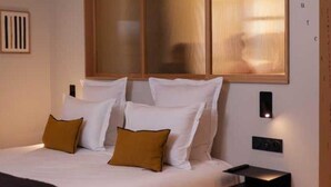 A modern bedroom with a large bed, wooden headboard, and a bedside table with a lamp. - Hotel Tinah: Elegance and Comfort Near the Champs-elysees (Paris)